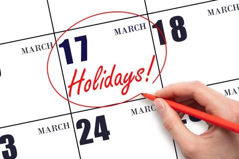 Hand drawing a red circle and writing the text Holidays on the calendar date  Stock Photos