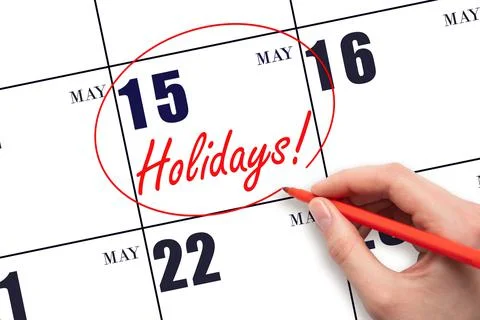 Hand drawing a red circle and writing the text Holidays on the calendar date  Stock Photos