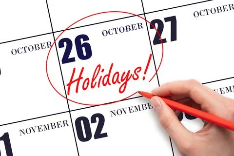 Hand drawing a red circle and writing the text Holidays on the calendar date  Stock Photos