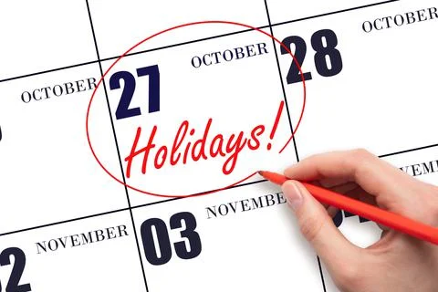 Hand drawing a red circle and writing the text Holidays on the calendar date  Stock Photos