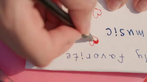 Hand Drawing Red Hearts and Writing My Favorite Music on White Paper Over Pink Stock Footage 345975825
