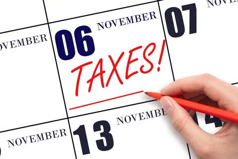 Hand drawing red line and writing the text Taxes on calendar date November 6. Stock Photos