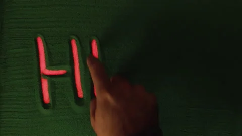 Hand drawing the Word Hell in the Green Sand with red backlight. Vídeos de archivo 209953407