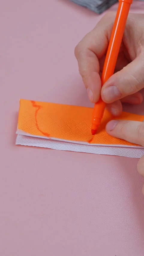 Hand drawing a zigzag toothed face with orange marker on a folded paper napki Video stock 347105115