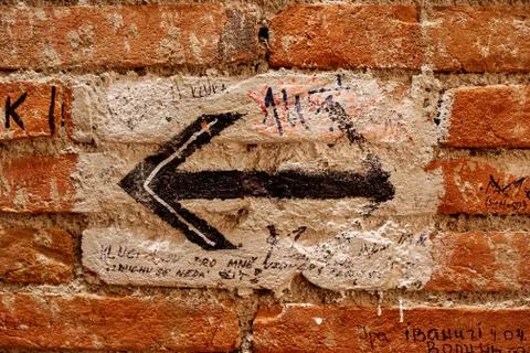 Hand drawn arrow pointing to the left on a brick wall in a dark room Stock Photos