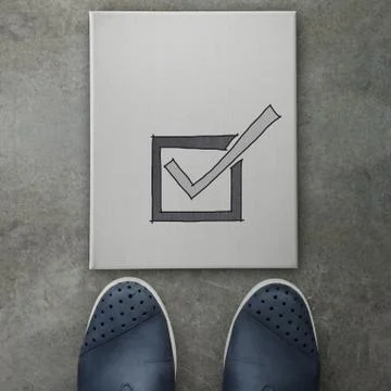 Hand drawn check mark  icon on canvas board on front of business man feet as  Stock Illustration