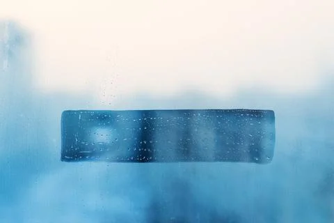 Hand drawn doodle shape rectangle for text on muddy blue glass wet window i.. Stock Photos