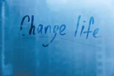 Hand drawn message Change life on foggy glass in city blue window Stock Photos