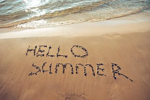 Hand drawn message Hello summer on wet yellow sand on beach of sea Stock Photos