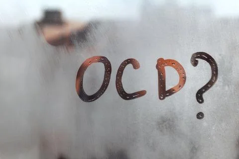 Hand drawn message OCD and question mark on foggy glass on suset window Stock Photos