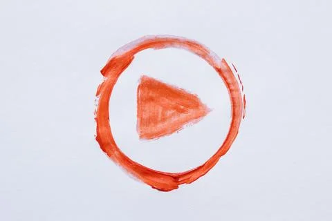 Hand drawn orange play button symbol in circle painted with brush on white Stock Photos
