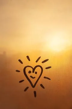 Hand drawn orange shape heart like sun with happy smile face on muddy glass wet Stock Photos
