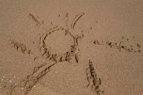 Hand drawn sun shape on a sandy beach Stock Photos