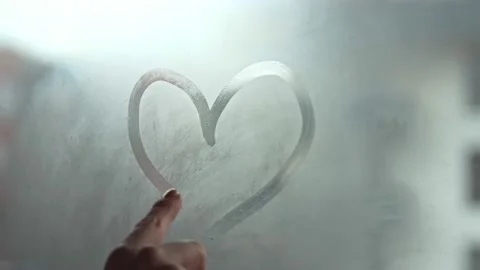 A hand draws a heart shape on the window with her finger. Fell in love. Stock Footage 144825208