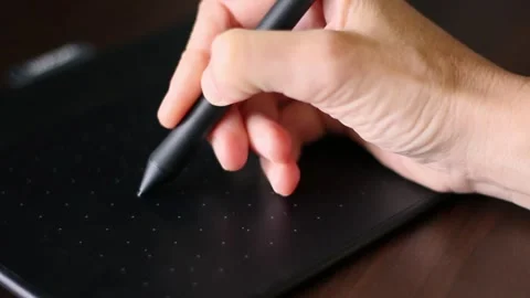 A hand draws with a stylus on a graphics tablet Stock Footage 252532722