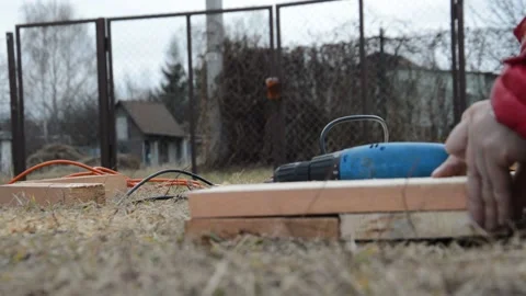 A hand drill drives self-tapping screws into a wooden plank Видео 165665515