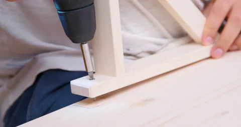Hand with drill screwing self-tapping screw piece wooden furniture fixes mount Stock Footage 208223969