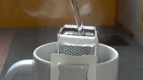 Hand drip hot coffee in mug with heat steam daytime. Pouring hot boil water. Stock Footage 310660386