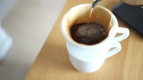 Hand Dripping Hot Coffee into a White Mug on Table Stock-Footage 330174794