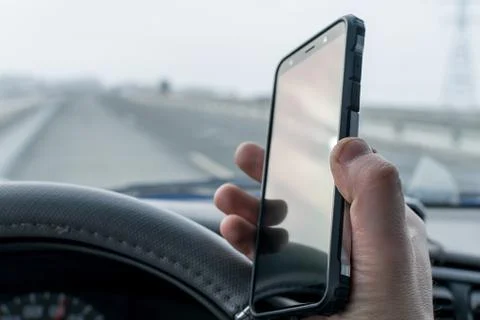 In the hand of the driver of the car, a cell mobile phone Stock Photos