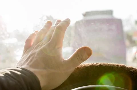 The hand of the driver of the car covers the sunlight, which blinds Stock Photos