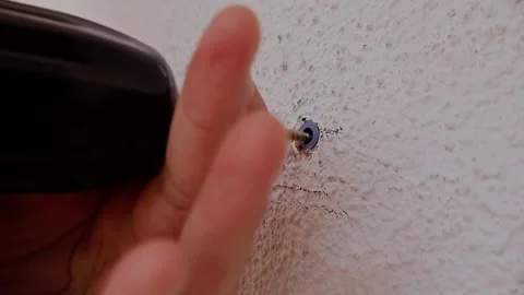 Hand drives screw into textured wall Stock Footage 345175558