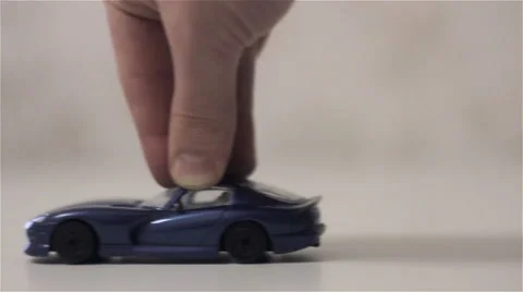 A hand drives a toy sport car Stock Footage