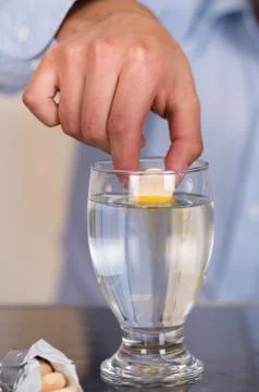 Hand drooping a pill effervescent tablet in a glass of water 스톡 사진