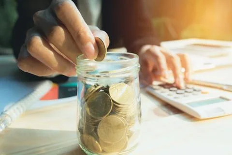 Hand drop the coin in jar with stack coins. Financial, accounting and saving  Stock Photos
