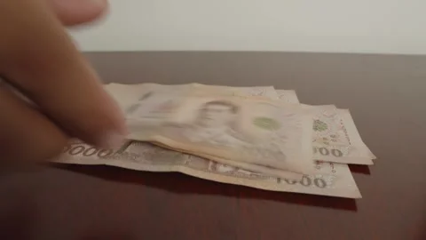 Hand drop a lot of thousands Thai baht banknotes money on wood table. Stock Footage 243890796