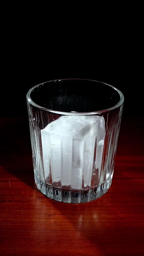 Hand Dropping Large Ice Cube into Empty Glass Slow Motion Stock Footage 324599651