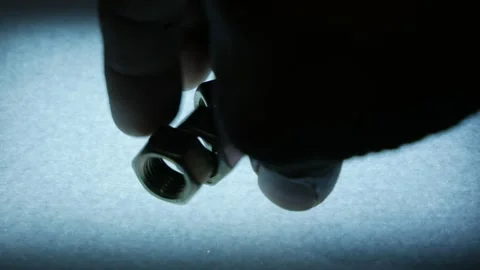 Hand Dropping Multiple Large Metal Hex Nuts onto Textured Surface Stock Footage 340068952