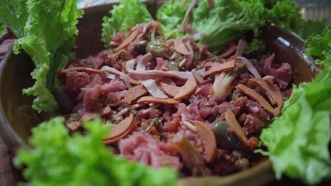 Hand dropping slices of ham over red curtido during Guatemalan fiambre preparati Stock Footage 318378953