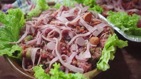 Hand dropping strips of ham over Guatemalan fiambre Stock Footage 319001612