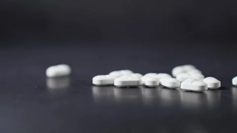 Hand Dropping White Pills on Dark Surface Stock Footage 303512330