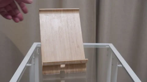 Hand Drops Bamboo Tablet Stand Onto Glass Table with a Sharp Woody Clack Stock Footage 321345961