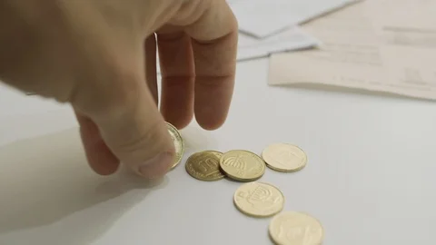 Hand drops coins on table with bills in BG - cents or Agorot Stock Footage 108835997