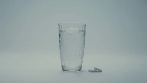 Hand drops a effervescent pill that dissolves in a glass of water Stock Footage 71484379