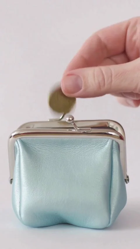 Hand drops a gold coin into small blue purse Stock Footage 334183818