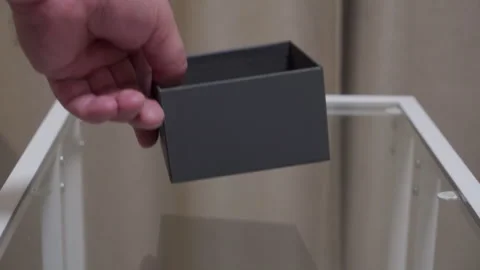 Hand Drops Small Gray Box onto Clear Glass Table with a Hollow Thud Stock Footage 321345969