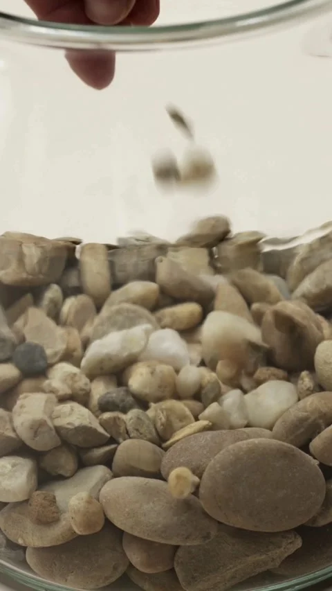 Hand drops small pebbles into a jar of water 库存影片 331770237