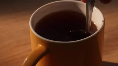 Hand drops sugar cube into cup of black tea and stirring Stock Footage 312278744