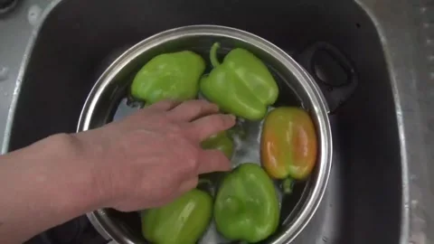 A hand drops a sweet pepper into a pot of water Video stock 311519261