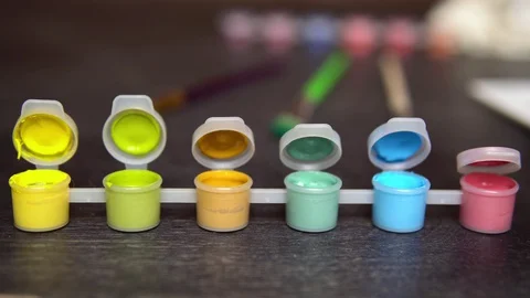 Hand dunks blue brush in yellow green acrylic paint on a dark table Stock Footage 129890990