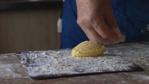 A hand dusts flour over a fresh syrniki patty on a rustic kitchen board, sh.. Stock Footage 339849157