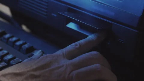 Hand Ejecting Floppy Disk from Computer in Cinematic Blue Lighting Stock Footage 348914177
