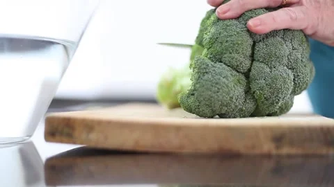 Hand of an elderly person cutting a green broccoli and putting it in a container Stock Footage 172217276