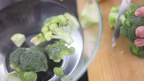 Hand of an elderly person cutting a green broccoli and putting it in a container Stock Footage 172217291