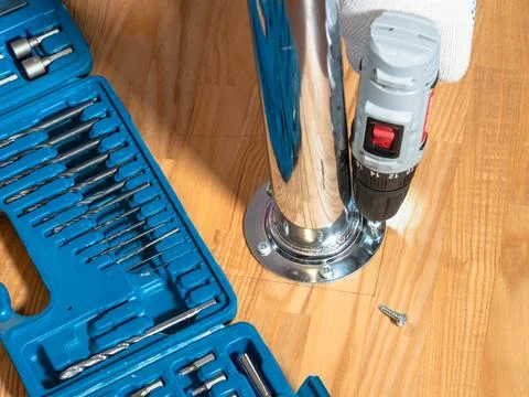 Hand with electric screwdriver fixes table support Stock Photos