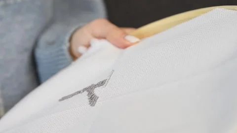 Hand embroidering black thread cross stitch on white fabric in neutral tone.. Stock Footage 334955264